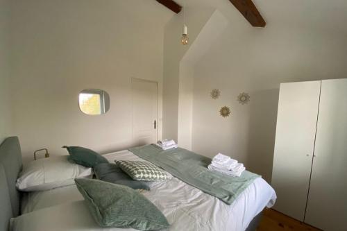Un dormitorio con una cama con almohadas verdes. en La Petite Maison, en Charly