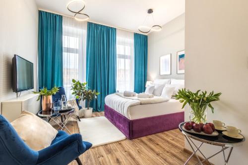 a bedroom with a bed and a living room with blue curtains at Hotel Sofia by The Railway Station Wroclaw in Wrocław