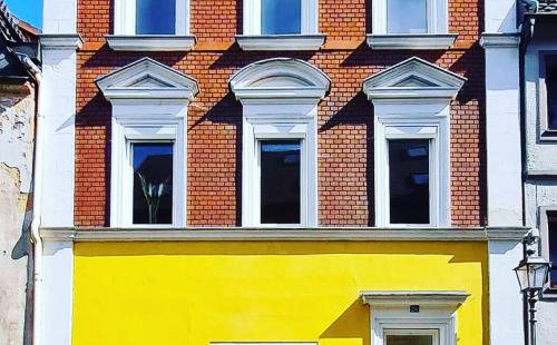 a yellow building with five windows on a brick building at Alte Färberei - Wohnen in der Altstadt in Kulmbach