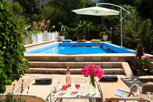 un patio con una mesa con flores y una piscina en Waterfront Cottage, en Marmaris