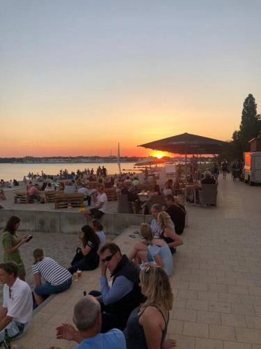 a group of people sitting around watching the sunset at Sonnendeck / 3 Zi.-FeWo mit Meerblick in Toplage in Neustadt in Holstein