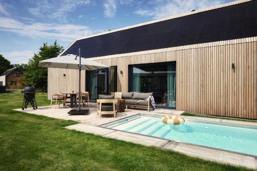 un patio trasero con piscina y una casa en Resort de Weelderik, en Hengelo
