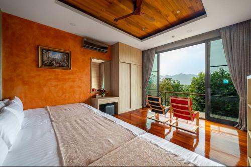 1 Schlafzimmer mit einem großen Bett und 2 Stühlen in der Unterkunft Suite R4-5 The Height Khaoyai 2BR byน้องมังคุด in Ban Huai Sok Noi
