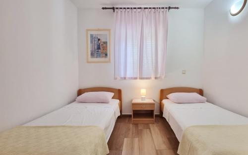 two twin beds in a room with a window at Apartments Barbalic D in Baška