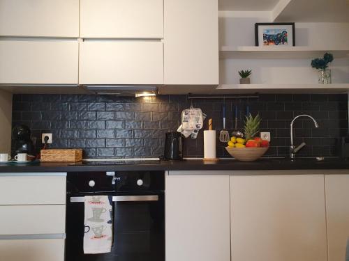 uma cozinha com armários brancos e uma parede de azulejos pretos em Korado Studio Apartment em Vrsar