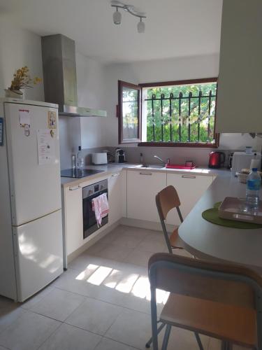 une cuisine avec un réfrigérateur blanc et une table dans l'établissement Villa Nancea Bassin Arcachon Gujan Mestras, à Gujan-Mestras