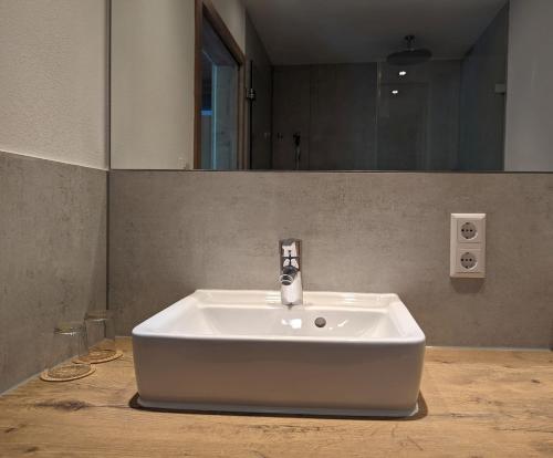 a white sink in a bathroom with a mirror at Apartments Fischerklause am Bodensee in Wasserburg am Bodensee