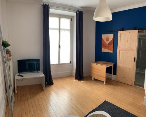 ein Wohnzimmer mit einer blauen Wand und einem TV in der Unterkunft La Maison d'Emilie - Appartements in Chaumes-en-Brie