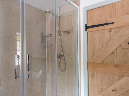 a shower with a glass door in a bathroom at Swallows Barn in Totnes