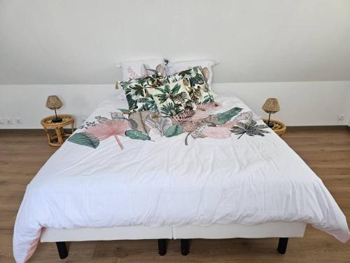 Una cama con sábanas blancas y almohadas tropicales. en Gite Le haut du Caraquet, en Desvres