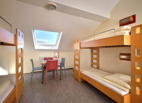 a room with bunk beds and a table and chairs at Youth Hostel Lultzhausen in Lultzhausen