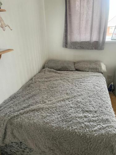 Una cama en un dormitorio con una manta gris y una ventana en Ultimate Cozy Room, en Kirkstall