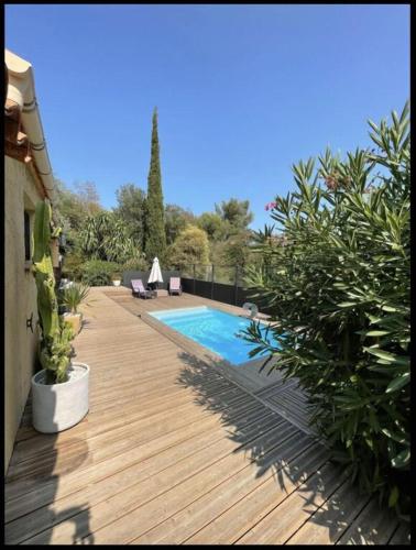 une terrasse en bois avec une piscine et quelques plantes dans l'établissement Belle maison vue montagne avec piscine privée à 5 minutes de la mer et village.i, à Bormes-les-Mimosas