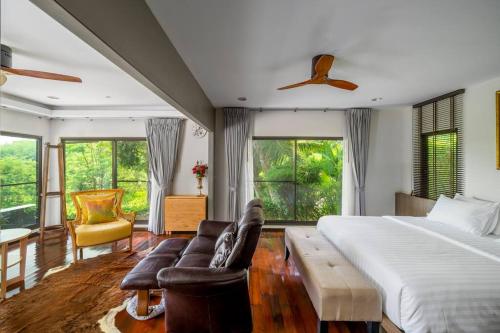 ein Schlafzimmer mit einem Bett, einem Sofa und Fenstern in der Unterkunft Villa Jacuzzi R6 The Height Khaoyai 1BR byน้องมังคุด in Ban Huai Sok Noi