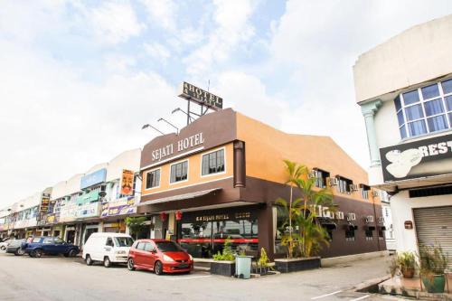 a street with cars parked in front of a store at Sejati Hotel in Sitiawan