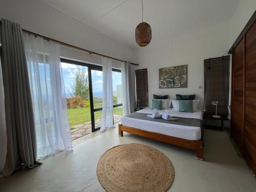 a bedroom with a bed and a large window at COCO MANGO Villa in Trèfles
