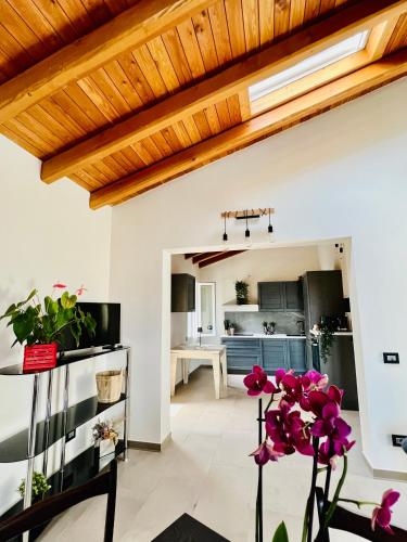 a living room with a wooden ceiling and purple flowers at La Rocchetta B&B in Rocchetta