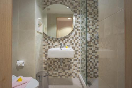a bathroom with a sink and a toilet and a mirror at Regantris Surabaya in Surabaya