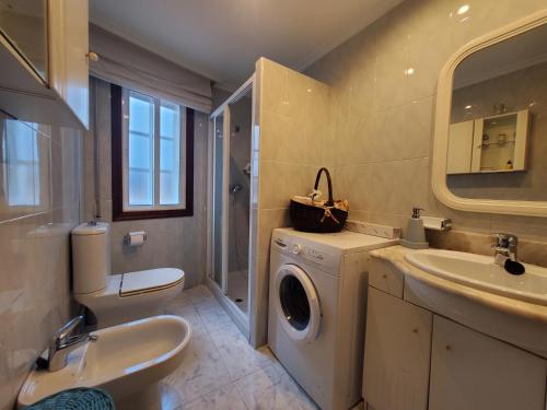 een badkamer met een wasmachine en een wastafel bij Apartamento playa Sanxenxo in Sanxenxo