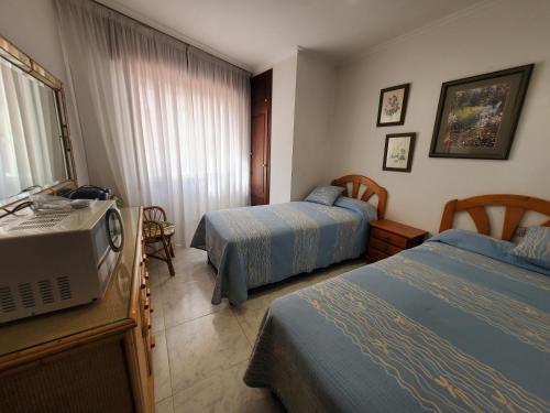 een hotelkamer met 2 bedden en een televisie bij Apartamento playa Sanxenxo in Sanxenxo