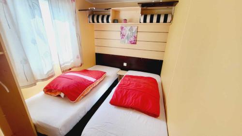 two beds in a small room with red and white pillows at Le Costa Gloria - Sud Nantes Camping de la Prairie in Saint-Hilaire-de-Riez