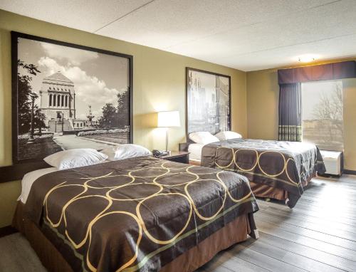 a hotel room with two beds and a picture of a building at Super 8 by Wyndham Indianapolis South in Indianapolis