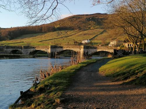 a bridge over a river with a hill in the background at Wharfe View B&B in Burnsall
