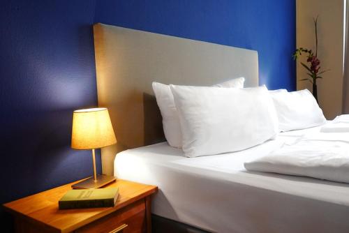 a bed with white pillows and a table with a lamp at Aparthotel Mitte in Dresden