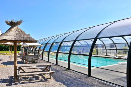 - un bâtiment avec un banc à côté d'une piscine dans l'établissement Camping Le Clairmarais, à Clairmarais