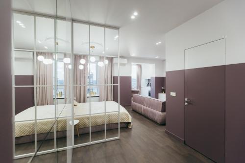 1 dormitorio con 1 cama con pared de cristal en Atlant luxury VIOLET Apart on Golovna стильні апартаменти поряд з ТЦ ДЕПОТ БЕЗКОНТАКТНЕ ЗАСЕЛЕННЯ en Chernivtsi