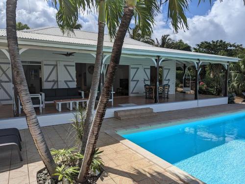 ein Haus mit Swimmingpool und Palmen in der Unterkunft Villa TOMCO in Deshaies
