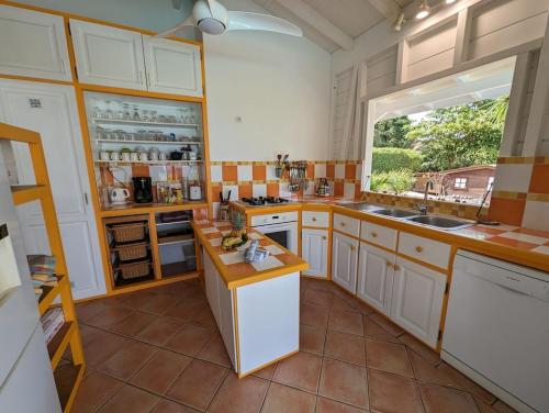 eine große Küche mit weißen Schränken und einem Fenster in der Unterkunft Villa TOMCO in Deshaies