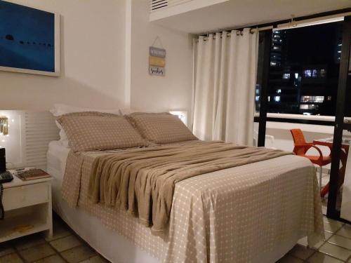 Schlafzimmer mit einem Bett, einem Fenster und einem Tisch in der Unterkunft Studio encantador com vista mar in Salvador