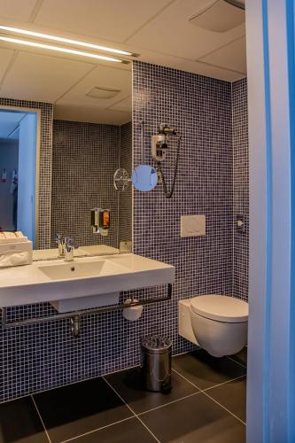 a bathroom with a sink and a toilet and a mirror at Hotel Thermana Park Laško**** Superior in Laško