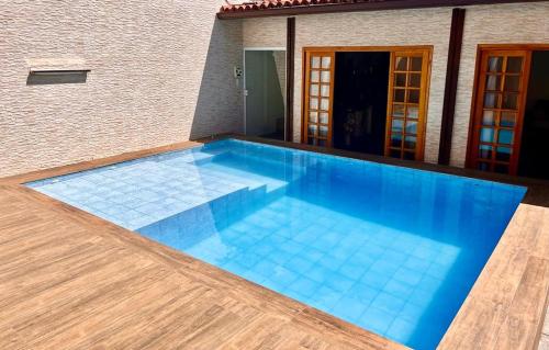 a swimming pool with blue water in front of a house at Quarto c/ Banheiro próximo a Praia da Barra da Tijuca in Rio de Janeiro