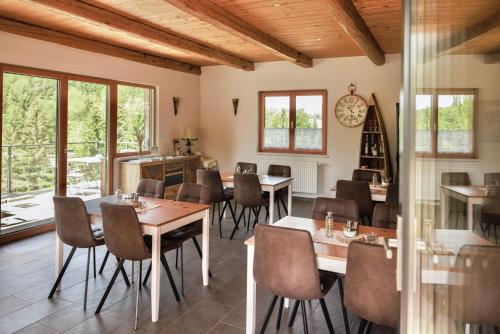 a dining room with tables and chairs and windows at Bauernhof Kure in Leutschach