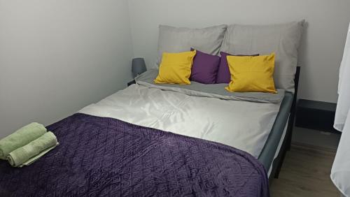 a bed with yellow and purple pillows on it at Przytulny apartament na Gdańskiej Starówce in Gdańsk