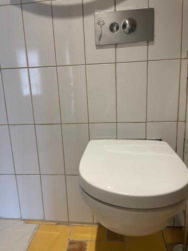 a white toilet in a bathroom with white tiles at Stebuklas coliving in Vilnius
