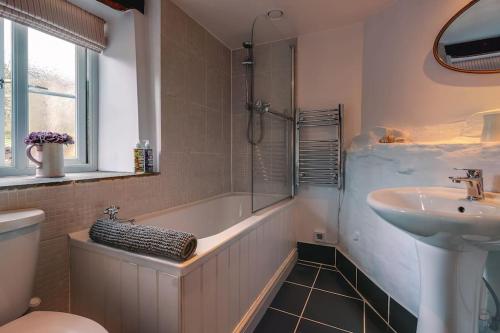 a bathroom with a tub and a sink and a shower at Woodpecker Cottage in Blakeney