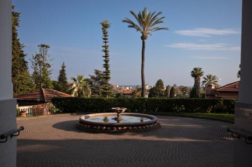 a fountain in the middle of a courtyard with a palm tree at Blu Apartment in Historical Hunbury in Bordighera