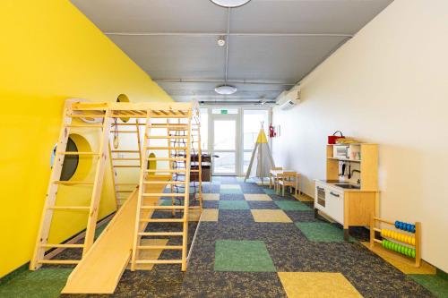 a room with a bunk bed and a yellow wall at Aqua Apartment Šventovė, By Cohost in Palanga