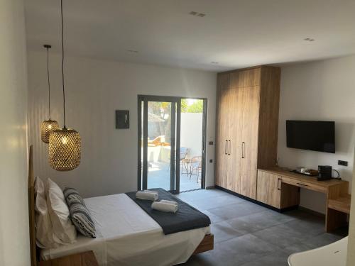 Schlafzimmer mit einem Bett, einem Schreibtisch und einem TV in der Unterkunft Sydney Hotel in Kefalos