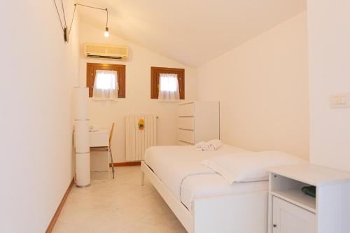 a small white bedroom with a bed and a desk at La terrazza di Giulietta in San Giovanni Lupatoto