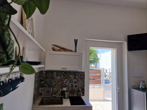 a white kitchen with a sink and a window at Camere A Oriente II in Torre dell'Orso