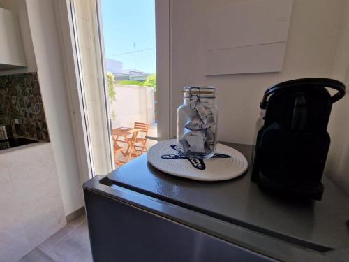 a jar on a counter with a plate and a kettle at Camere A Oriente II in Torre dell'Orso