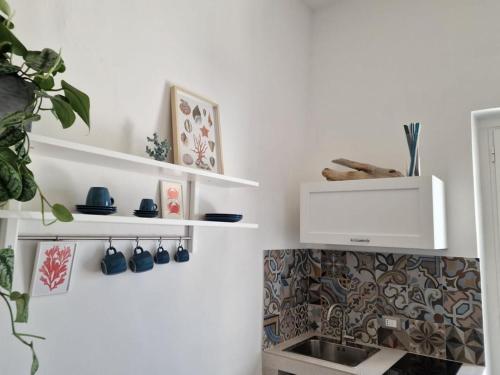 a kitchen with white shelves and a sink at Camere A Oriente II in Torre dell'Orso