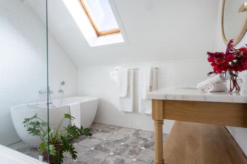 ein Badezimmer mit einer weißen Badewanne, einem Waschbecken und einer Badewanne in der Unterkunft Rozendal Stay in Stellenbosch
