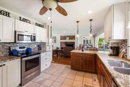 a kitchen with white cabinets and a ceiling fan at Lake Escape Lakefront Lodge at Red Bud Cove in Hollister