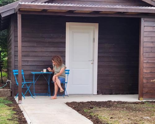a woman sitting at a table in a shed at Casa Gila in Yonatan