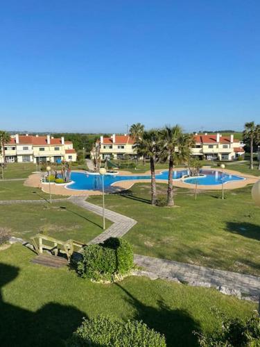 a park with a swimming pool and some palm trees at Villa avec piscine dans un golf in Palmela